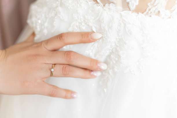 裁剪照片的女人触摸白色婚纱刺绣与温柔的花卉图案与手与白色指甲。图片下载