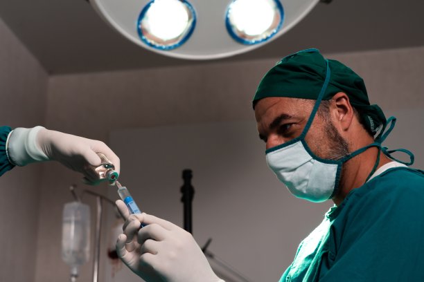 外科医生在无菌手术室从小瓶中填充注射器进行手术。图片下载