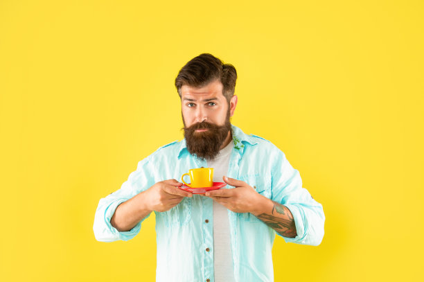 不刮胡子的男人，穿着黄色背景的咖啡衬衫，咖啡师图片下载