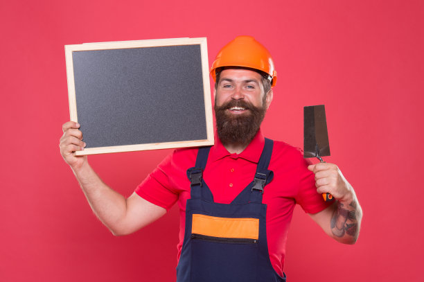 创造完美的表面。专业的泥水匠。熟练的泥水匠。成功的改造。带抹灰工具的大胡子工人。戴着安全帽的泥瓦匠时髦的建筑工人保持黑板复制空间图片下载