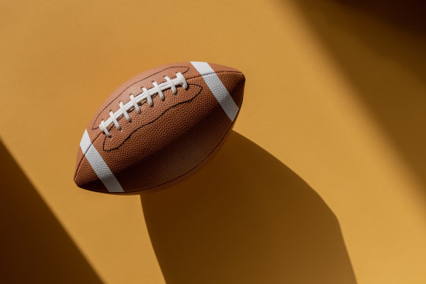 美式足球皮革球在黄色背景。前视图。游戏设备水平运动主题海报，贺卡，标题，网站和应用程序图片下载