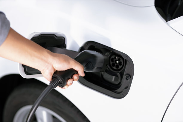 特写焦点手插入电动汽车充电器逐步电动可充电汽车。图片下载