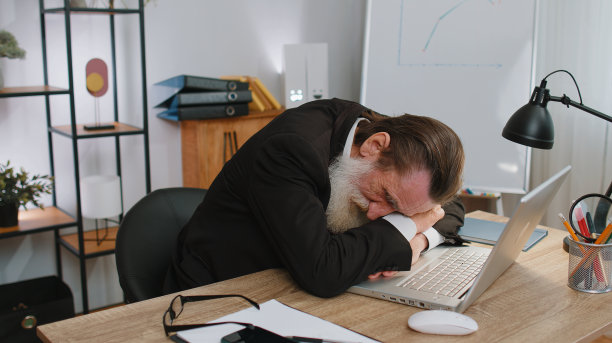 无聊困倦的商务人士在笔记本电脑上工作，打哈欠，在办公室睡着图片下载