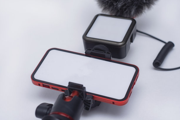 一套博客小工具。智能手机模型，白色屏幕，三脚架，白色背景上有灯和麦克风。图片下载