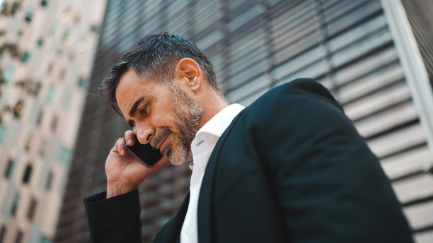 穿着办公服，留着整齐胡子的中年商人正在使用手机。成功男士在智能手机上深情交谈。失望,麻烦图片下载