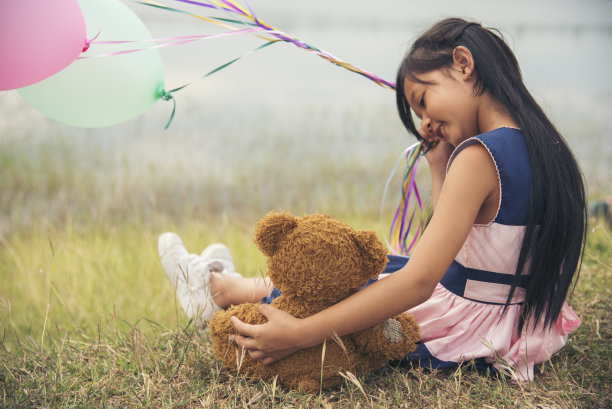 快乐的孩子在绿色公园操场上抱着泰迪熊。泰迪熊是小孩最好的朋友，可爱的女孩。自闭症快乐有趣，一起在操场上玩耍，在幸福的家庭里感受爱和温暖的拥抱图片下载