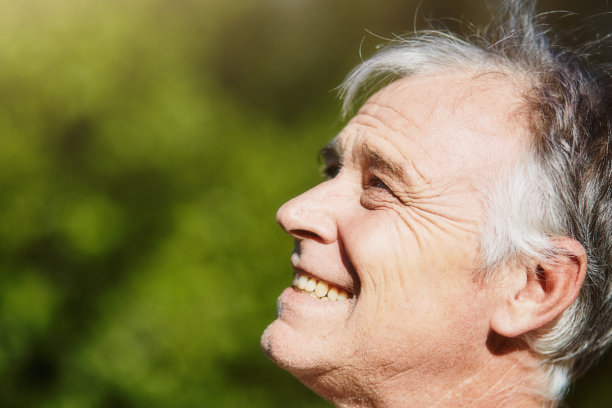在一个阳光明媚的户外大自然里，一个快乐的人露出灿烂的笑容，看起来欣喜若狂图片下载