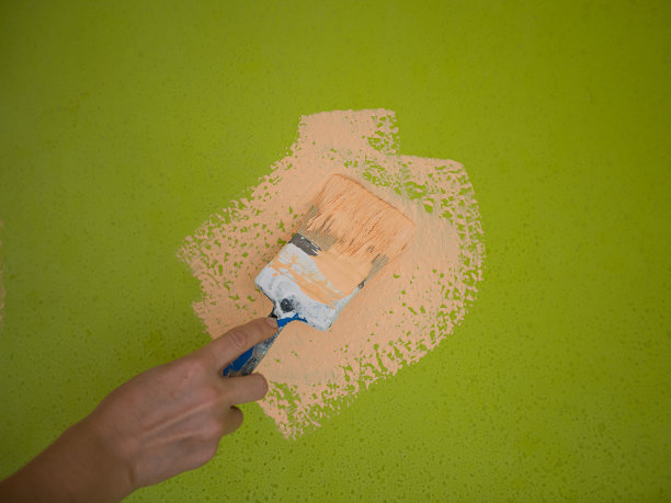 手持毛笔粉刷木墙。图片下载