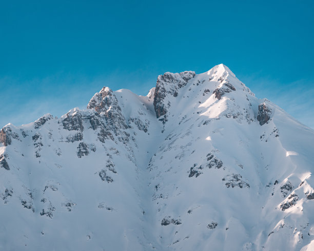 这张美丽的照片拍摄了一座在冬天被雪覆盖的岩石山顶图片下载