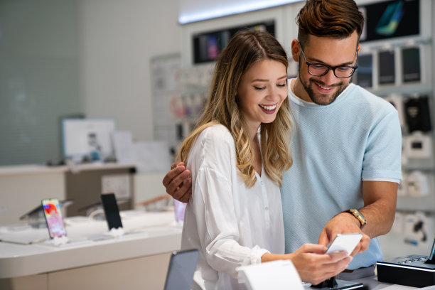 科技购物设备的概念。快乐的年轻人在手机商店购买新的智能手机。图片下载