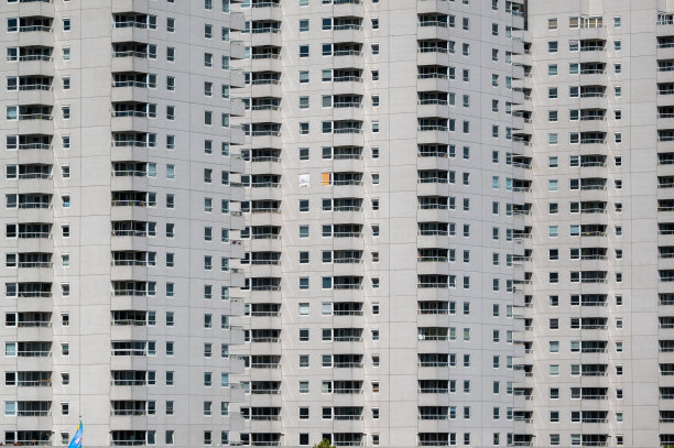 单调的高层公寓楼外立面用橙白色的窗帘，其他都是深黑色图片下载