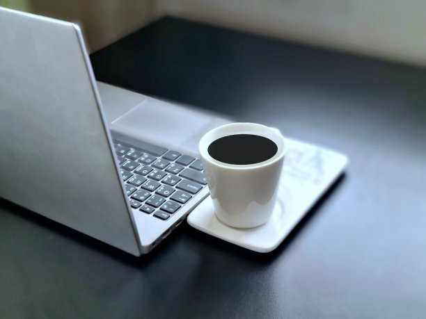 笔记本电脑放在办公室的黑色桌子上，还有一杯咖啡图片下载