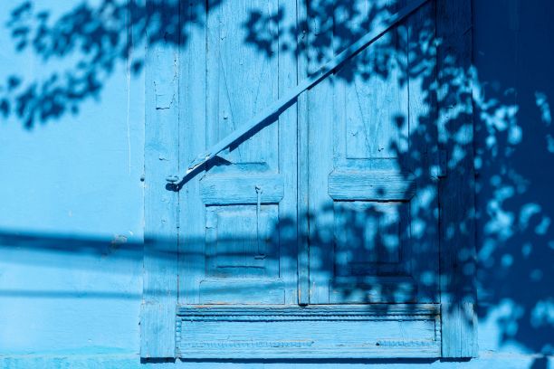 古老的蓝色木门上有树叶的影子和阳光图片下载