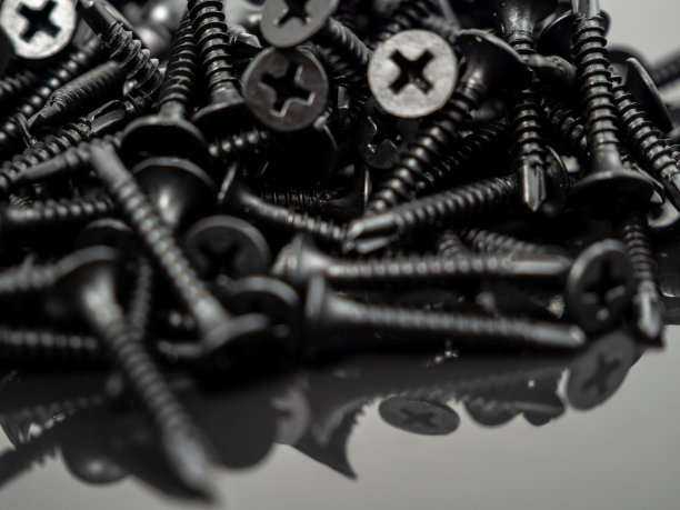 黑色背景上石膏板的黑色螺丝。图片下载