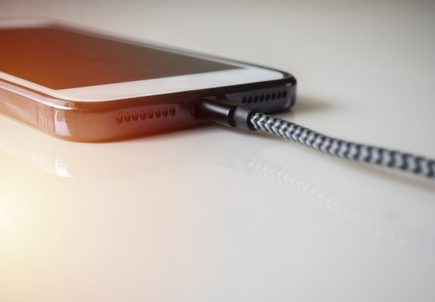 智能手机连接usb充电线，米色背景快速充电。图片下载