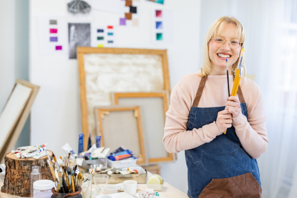 年轻的画家拿着画笔站在画室里图片下载