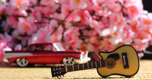 特写镜头的小装饰吉他与一辆老式汽车和樱花的背景图片下载