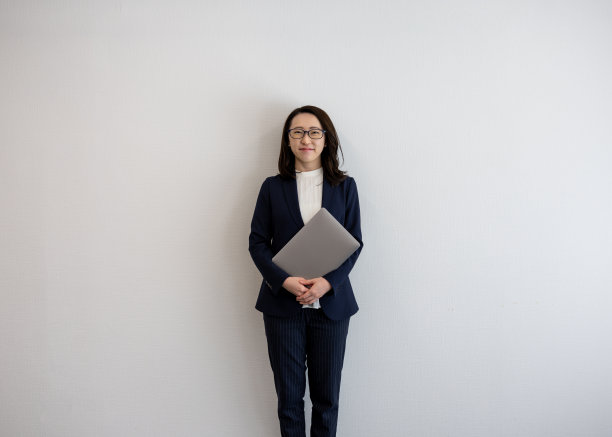 全长肖像女企业家站在米色背景，拿着笔记本电脑图片下载