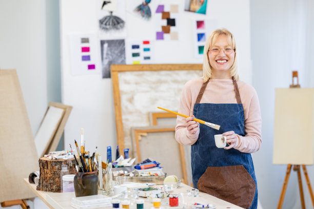 年轻的画家拿着画笔站在画室里图片下载