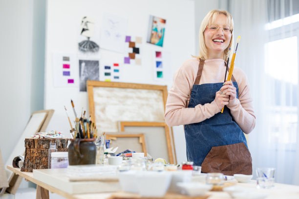 年轻的画家拿着画笔站在画室里图片下载