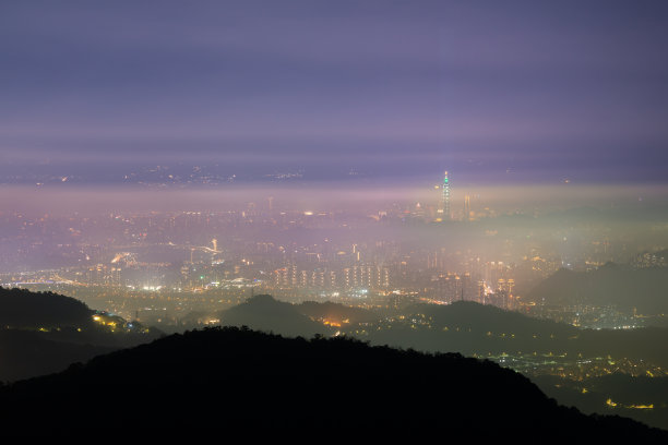 云在夜间在天空中移动。霓虹灯照亮了充满活力的城市景观。图片下载