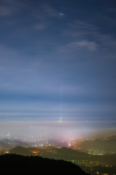 云在夜间在天空中移动。霓虹灯照亮了充满活力的城市景观。图片下载