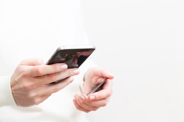 白色背景下女性手持信用卡和使用智能手机的特写镜头。女性在网上安全支付，使用银行服务，在网上商店订购。网上购物图片下载