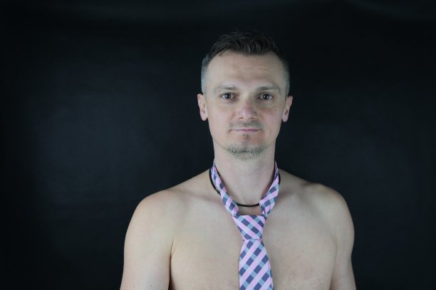 一名系着粉红色格子领带的白人青年正在摄影棚拍摄照片。图片下载