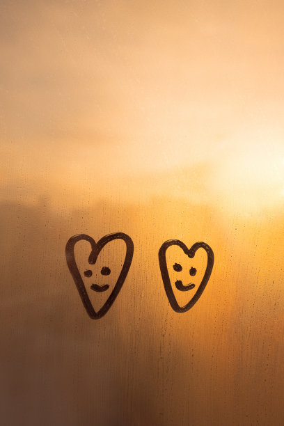 雾蒙蒙的玻璃上日落窗口与两个画笑脸心形概念照片图片下载