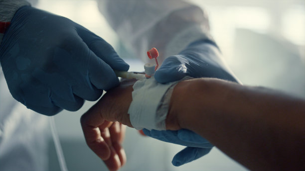 医生在病房调整点滴。病人手与静脉导管特写。图片下载