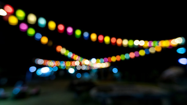 复古色调模糊图像的大排档在夜间节日与散景的背景使用。节日活动派对与人模糊的背景。图片下载