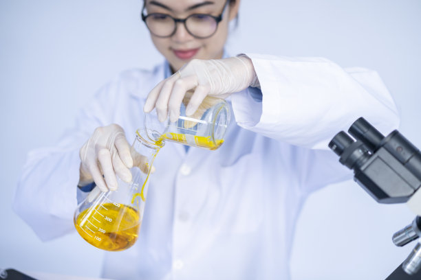 实验室研究员拿着装有黄色液体的医用玻璃瓶，女科学家在工作。图片下载