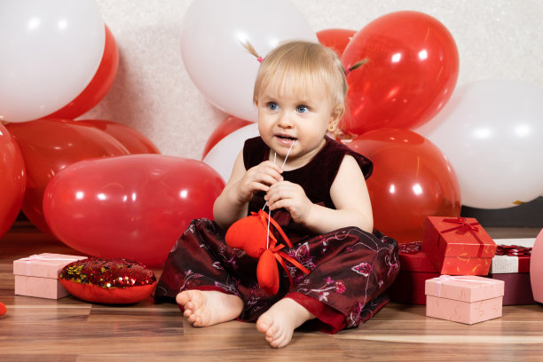 可爱的金发小女孩在情人节玩木棍上的心。图片下载