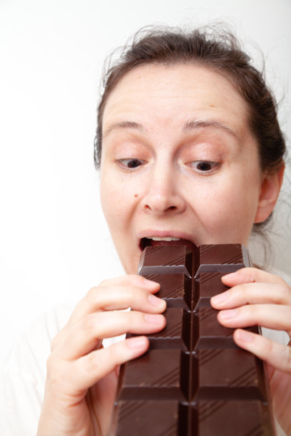年轻女子正在咬一大块巧克力图片下载