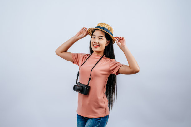年轻美丽的旅行者女性戴着草帽，摆出数码相机图片下载