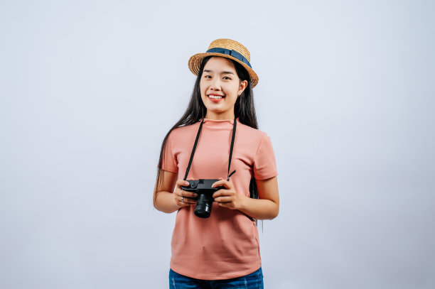 年轻美丽的旅行者女性戴着草帽，摆出数码相机图片下载