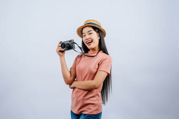 年轻美丽的旅行者女性戴着草帽，摆出数码相机图片下载