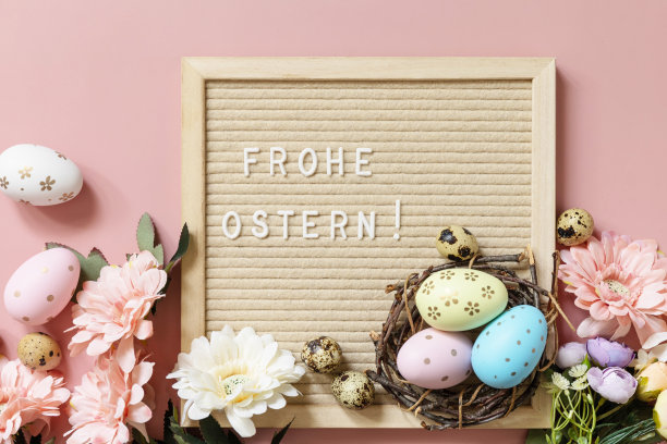 信板，Frohe Ostern -复活节快乐的德语问候，复活节彩蛋和春天的花朵在淡粉色的背景。从上面看。图片下载