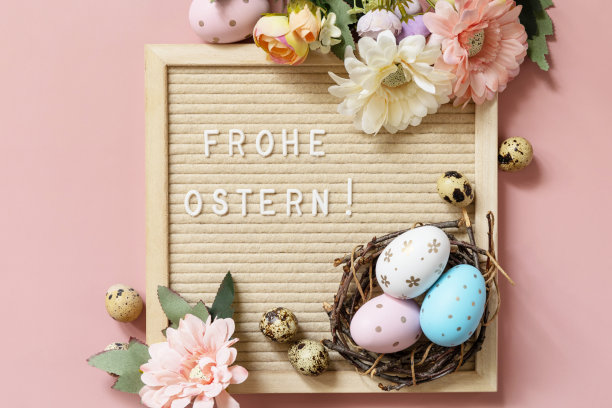 Frohe Ostern -德语复活节快乐，复活节彩蛋和春天的花朵在淡粉色的背景，极简主义风格的组成。从上面看。图片下载
