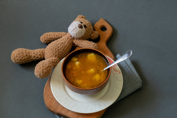 泰迪熊和一盘汤旁边的黑色背景图片下载