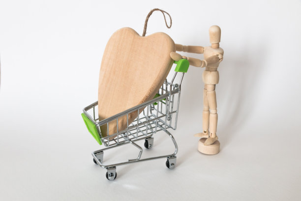 白色背景的商店里，一个木制人推着购物车里的一颗心图片下载