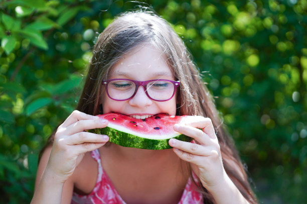 近距离的肖像年轻女孩笑，吃和享受西瓜。图片下载