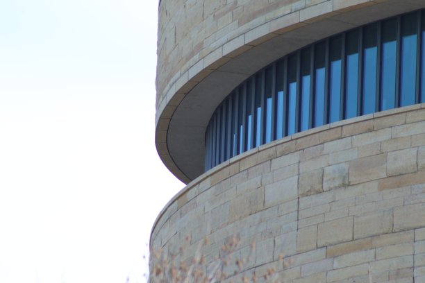 近景拍摄的现代圆形石灰华石建筑与蓝色玻璃窗与线条图片下载