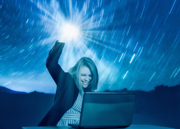摘星星!欣喜若狂的女人微笑着举起一盏明亮的灯，因为她成功地在她的笔记本电脑上图片下载
