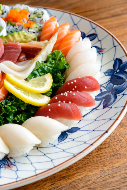什锦寿司和生鱼片在大古董手绘日本盘核桃木桌子图片下载