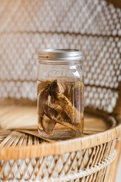 一个装有棕色香蕉皮和水的大玻璃罐子，作为自制的天然植物肥料或植物茶，为所有植物提供营养丰富的肥料，可持续，零浪费的生活方式图片下载