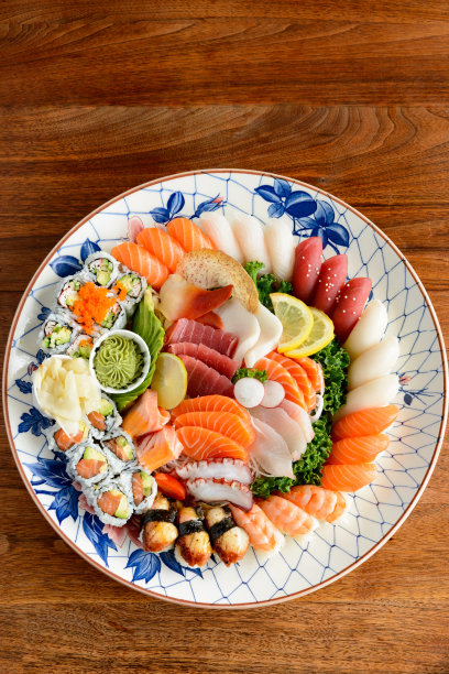 什锦寿司和生鱼片在大古董手绘日本盘核桃木桌子图片下载