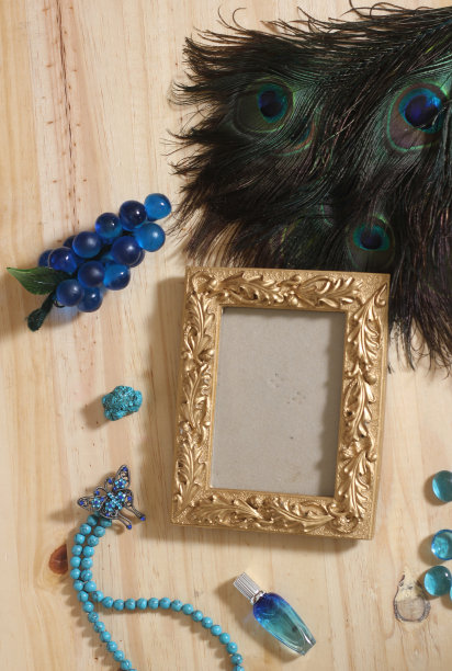 蓝色珠宝和孔雀羽毛与黄金相框复制空间的木桌图片下载