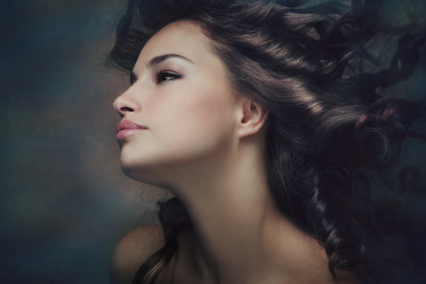 性感的黑发女人与闪亮的卷曲柔滑的头发在运动图片下载