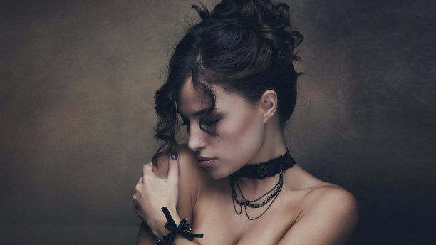 年轻漂亮的女人，深色波浪头发挽成圆髻，抱着她的肩膀图片下载